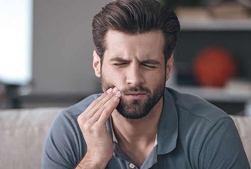 Man holding cheek in pain