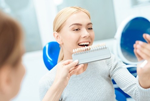 Woman's smile compared with tooth color chart