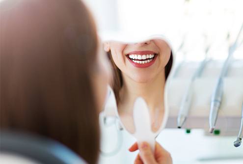 Woman looking at beautiful smile in mirror