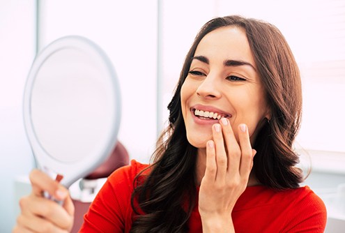 Patient admiring her smile after receiving dental crown