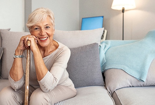 An older, smiling woman sitting on a couch