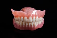 Full upper and lower dentures against black background