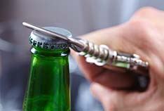 Closeup of patient using bottlecap opener to prevent dental emergencies in McMinnville