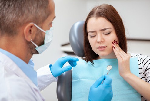 young woman in pain because she needs tooth extractions in McMinnville 