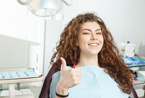 young woman giving thumbs up before receiving tooth-colored fillings in McMinnville 