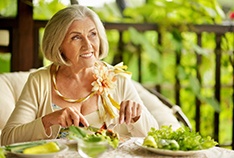 Senior woman enjoying meal with help of her dental implants