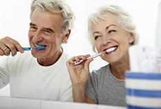 Senior couple brushing teeth, enjoying long-term benefits of dental implants