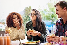 Group of friends smiling while eating lunch outside