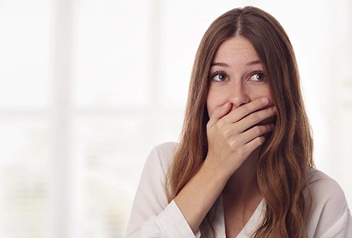 A young female with long, dark hair covering her mouth because of the imperfections