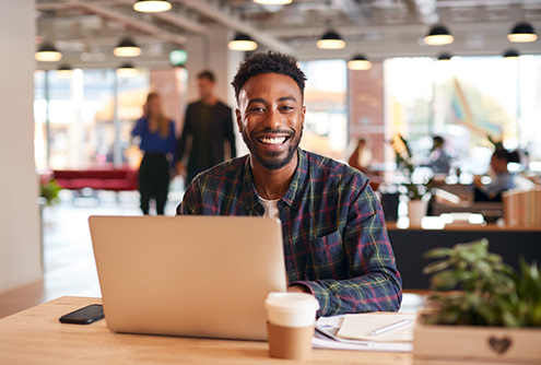 Man smiling while working on laptop in office