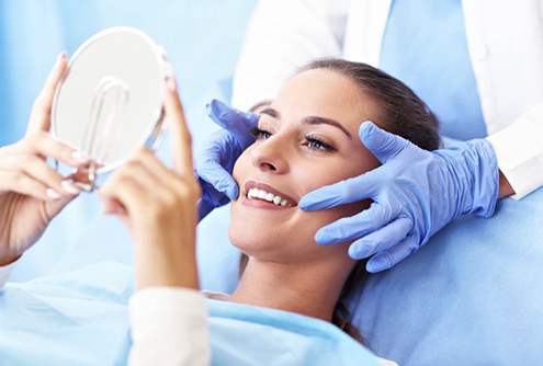 young woman admiring her metal-free dental restorations in McMinnville 