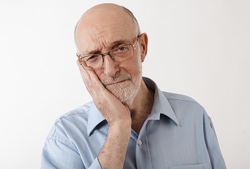 Older man holding cheek in pain