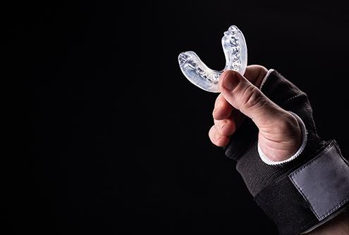 a hand holding up an athletic mouthguard
