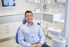 Man smiling in collared shirt in dental chair 