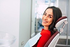 Woman in red shirt smiling in dental chair