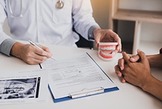 Dentist reviewing paperwork on the cost of veneers in McMinnville