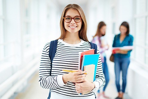 Young woman holding books in school hallway