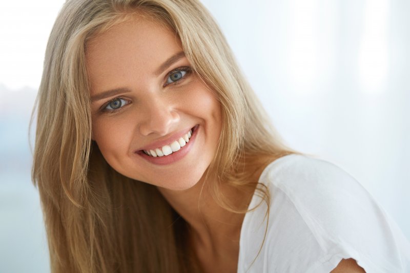 a young woman wearing a white shirt and showing off her healthy, damage-free smile