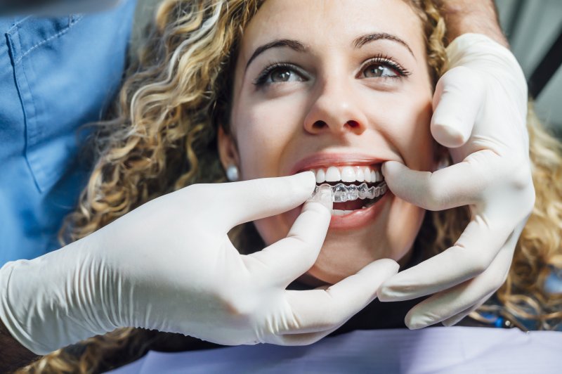 dentist putting Invisalign clear aligners on patient