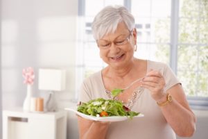 a woman eating healthy foods that are best for her dental implants 